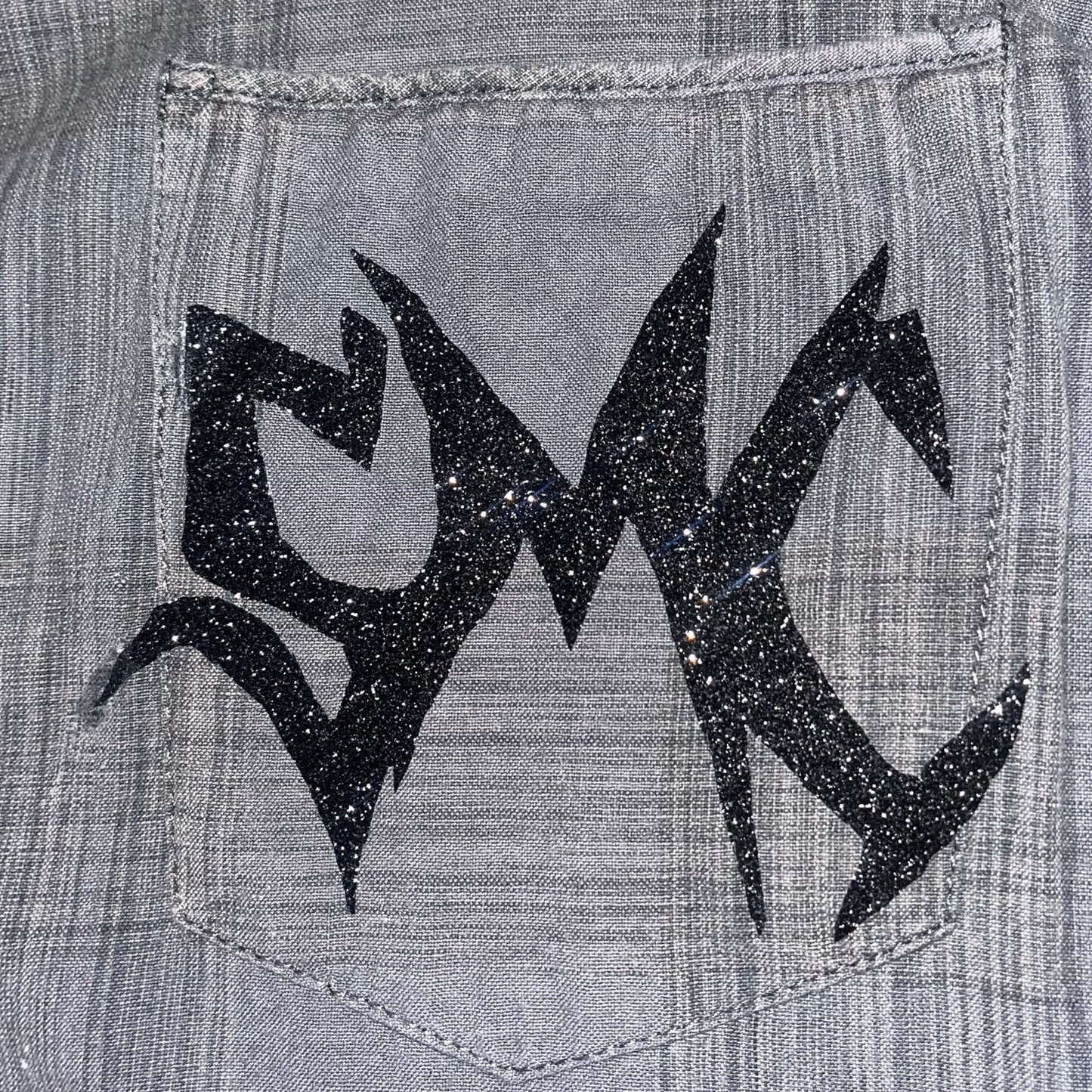 Close up of the sparkling SMC sigil adorned on the one-of-one "Grey Matter" button-up shirt by SMC